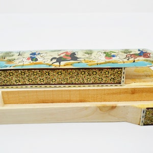 Puede incluir: Una caja de madera con una tapa con bisagras. La tapa est&aacute; decorada con una escena colorida de personas montando a caballo. La caja est&aacute; hecha de madera y tiene un patr&oacute;n decorativo en los lados.