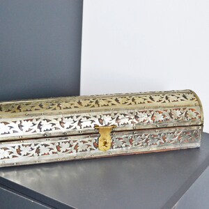 May include: A silver and gold decorative box with intricate floral patterns. The box has a hinged lid and a brass clasp.