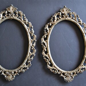 May include: Two ornate silver oval picture frames with intricate scrollwork designs.