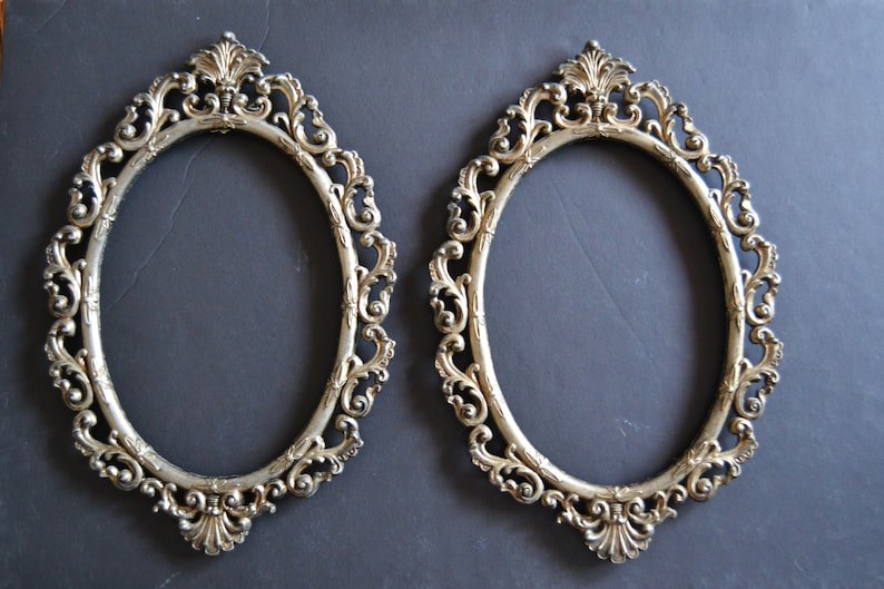 May include: Two ornate silver oval picture frames with intricate scrollwork designs.