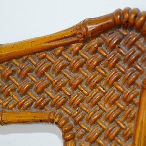 May include: Close-up of a woven bamboo chair back with a brown and orange colour scheme. The woven pattern is intricate and detailed.