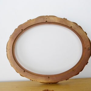 May include: A gold oval picture frame with a decorative, ornate design. The frame is made of wood and has a smooth finish.