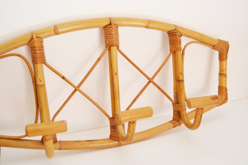 May include: A natural bamboo coat rack with a curved top and three hooks. The rack is made of woven bamboo and has a natural finish.