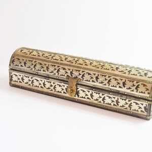 May include: A silver and gold decorative box with intricate floral patterns. The box has a hinged lid with a brass latch.