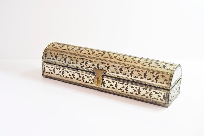 May include: A silver and gold decorative box with intricate floral patterns. The box has a hinged lid with a brass latch.