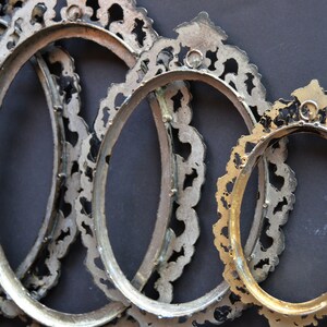May include: Four oval-shaped picture frames with ornate, silver-colored metal frames. The frames are nested together, with the smallest frame in the front and the largest frame in the back.