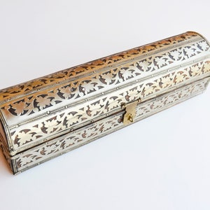 May include: A silver and gold decorative box with an ornate floral design. The box has a hinged lid and a brass lock.