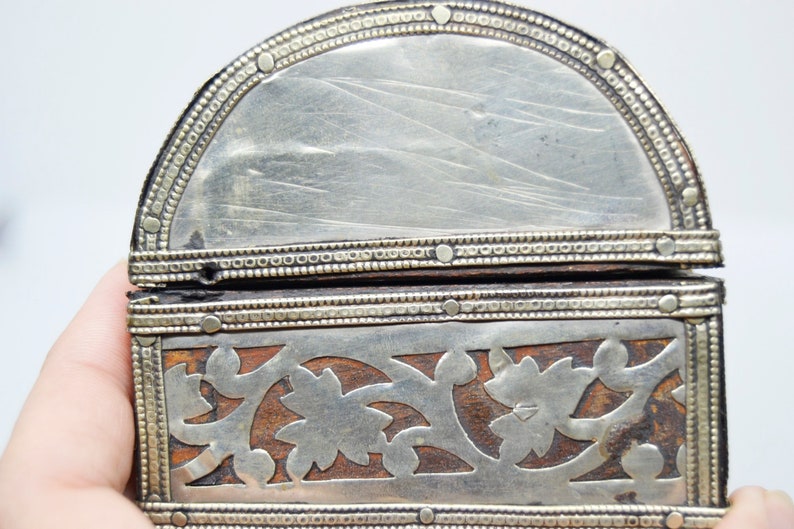 May include: A small, wooden box with intricate silver filigree designs. The box is hinged and has a silver-plated interior.