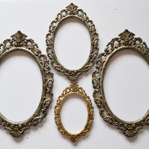 May include: Four ornate oval picture frames, three are silver and one is gold. The frames are all different sizes and have intricate designs.