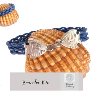 May include: A blue braided bracelet kit with silver fish charms and a lobster clasp. The kit is displayed on a seashell. The text "Bracelet Kit" and "Raquel Jimenez" is visible in the image.