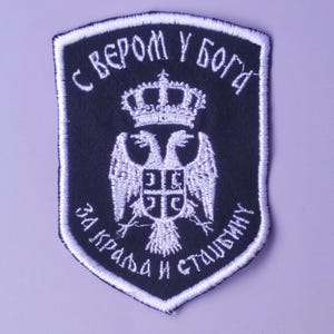 May include: A black embroidered patch with a white double-headed eagle, a crown, and the text "С ВЕРОМ У БОГА ЗА КРАЉА И СТАВЉАЊУ".