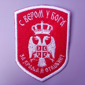 Op de afbeelding: Een rood geborduurd patch met een witte dubbelkoppige adelaar, een kroon en de tekst "S VEROM U BOGA ZA KRALJA I OTVIBINU".