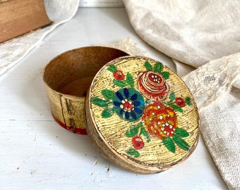 May include: A round wooden box with a hand-painted lid. The lid features a floral design with red, yellow, blue, and green flowers. The box is a vintage style and would be a great addition to any home decor.