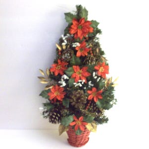 May include: A festive Christmas tree arrangement featuring vibrant red poinsettias, pine cones, and greenery. The tree is set in a woven red basket, creating a warm and inviting holiday decoration.