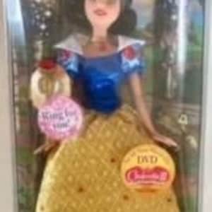 May include: A Snow White doll in a display box. The doll wears a blue top with white sleeves and a yellow skirt. The box includes two round stickers that read "King for you" and "DAD Celebrating".