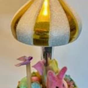 Könnte beinhalten: Ein vintage Weihnachtsbaumschmuck aus Glas mit einem weißen und gold gestreiften Karusselldach, einem rosa Hasen und pastellfarbenen Eiern in einem Nest.