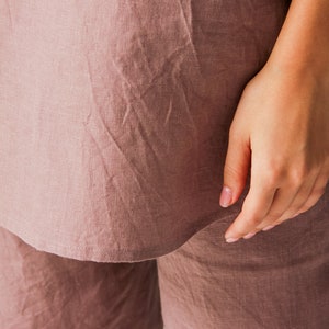 Op de afbeelding: Een mauve linnen top en broek set. De top heeft een ontspannen pasvorm en een licht gebogen zoom. De broek heeft een rechte pijp.