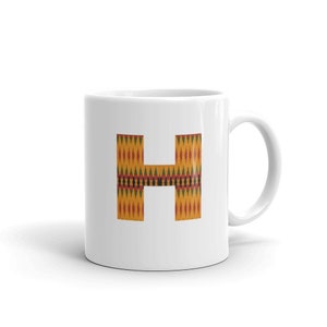 Puede incluir: Taza de cerámica blanca con una gran letra "H" impresa en la parte delantera. La letra está en un patrón geométrico amarillo, naranja, rojo y verde.
