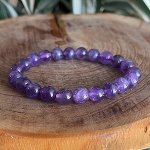 May include: A purple amethyst gemstone bracelet with round beads.