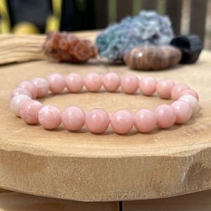 May include: A pink gemstone bracelet featuring round beads. The bracelet is crafted from natural stones and makes a lovely accessory for any occasion.