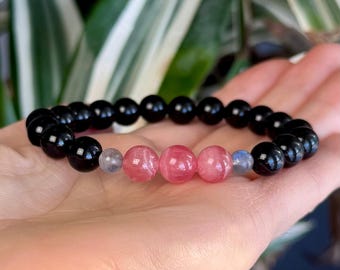 May include: A black beaded bracelet with pink and gray gemstone beads.