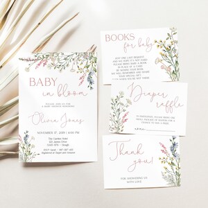 May include: A set of baby shower stationery with floral accents. The invitation reads "Baby in Bloom" and includes the name Olivia Jones and event details. Other cards include "Books for Baby," "Diaper Raffle," and "Thank You."