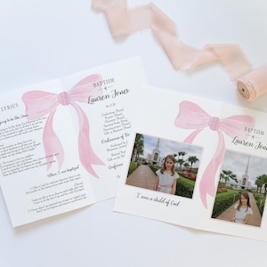 May include: Baptism announcement featuring a pink watercolor bow and the name "Lauren Jones." The announcement includes song lyrics, photos, and the text "I am a child of God." A roll of pink ribbon is in the background.