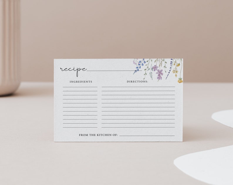 Puede incluir: Una tarjeta de receta en blanco con un dise&ntilde;o floral en tonos de morado, azul y amarillo. La tarjeta tiene l&iacute;neas para escribir los ingredientes y las instrucciones. El texto "receta" est&aacute; en la parte superior de la tarjeta. El texto "De la cocina de:" est&aacute; en la parte inferior de la tarjeta.