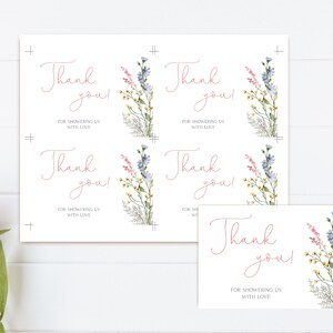 May include: White thank you cards with floral watercolor illustrations. The cards feature the text "Thank you! For showering us with love" in a delicate pink script. The floral design includes blue, pink, and yellow wildflowers.