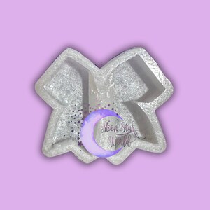 May include: White silicone mold shaped like a bow with a crescent moon and stars in the background. The text "Moon Star World" is visible in the image.