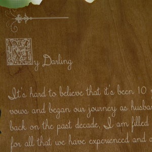 May include: A wooden sign with a decorative border and the text "y Darling It's hard to believe that it's been 10 years since we said our vows and began our journey as husband and wife. Looking back on the past decade, I am filled with gratitude for all that we have experienced and accomplished together.  I love you more than words can say."