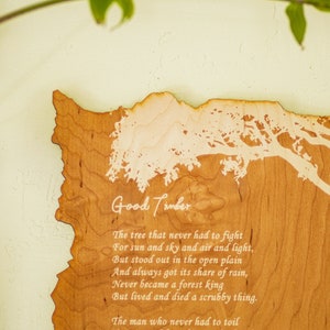 May include: A wooden plaque with the words "Good Timber" and a poem etched into the wood. The plaque is shaped like a state outline, with a tree design. The wood has a light brown color.