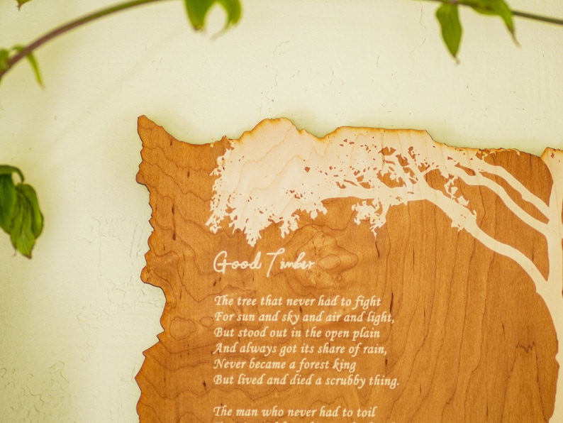 May include: A wooden plaque with the words "Good Timber" and a poem etched into the wood. The plaque is shaped like a state outline, with a tree design. The wood has a light brown color.