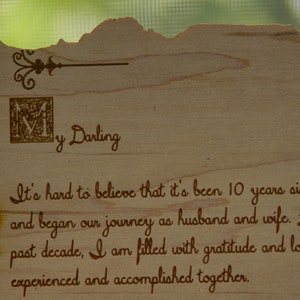 May include: A wooden sign with a burnt edge and a decorative flourish. The sign reads "My Darling It's hard to believe that it's been 10 years since we and began our journey as husband and wife. Looking past decade, I am filled with gratitude and love for experienced and accomplished together."