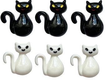 May include: Six black and white cat figurines. Three black cats with yellow eyes and three white cats with black eyes.