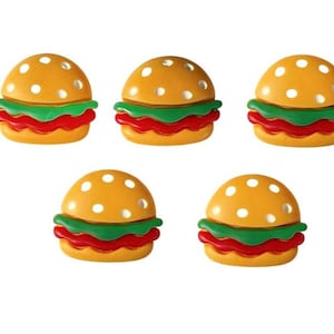 May include: Five yellow and white polka dot plastic hamburger buttons with green lettuce and red tomato accents.