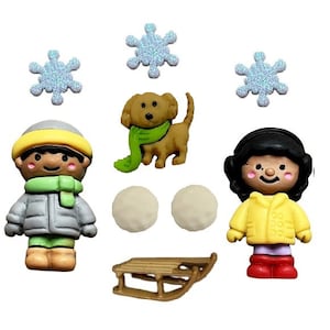 May include: A set of winter-themed buttons featuring a boy and girl in winter clothing, a dog wearing a scarf, snowballs, a sled, and snowflakes.