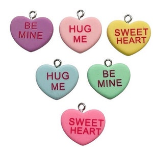 May include: Six heart-shaped charms with different colors and messages: purple "Be Mine", pink "Hug Me", yellow "Sweetheart", light blue "Hug Me", green "Be Mine", and pink "Sweetheart".