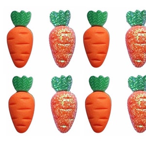 May include: Set of eight orange and green carrot shaped embellishments. The carrots are made of a sparkly material and have a green leafy top.