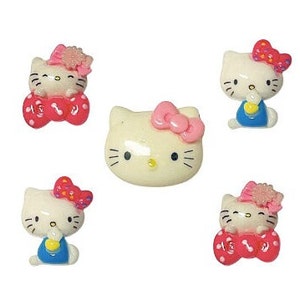 May include: Five white Hello Kitty charms with pink bows and pink and red accents. The charms are made of plastic and are about 1 inch tall.