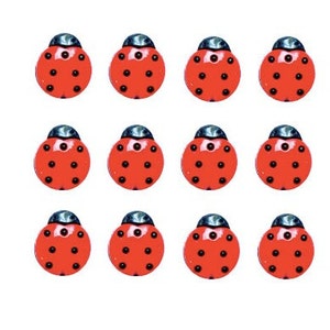 May include: Twelve red ladybug-shaped decorative objects with black spots and dark blue heads are arranged on a white background. The ladybugs are evenly spaced and appear to be made of a glossy material.