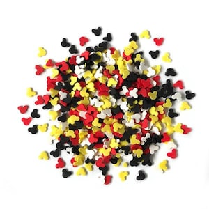 May include: A large pile of colorful Mickey Mouse head sprinkles in red, yellow, black, and white.