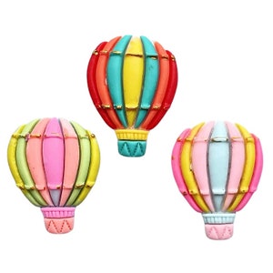 May include: Three colorful hot air balloon-shaped decorative items. Each balloon features a vibrant mix of colors, including red, yellow, pink, and blue, with gold accents. The balloons have a textured appearance and are set against a white background.