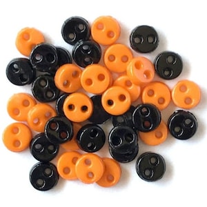 May include: A pile of small, two-hole buttons in black and orange.