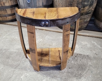 May include: A half-round wooden table with a metal band around the top and a shelf underneath. The table is made from reclaimed wood barrels.