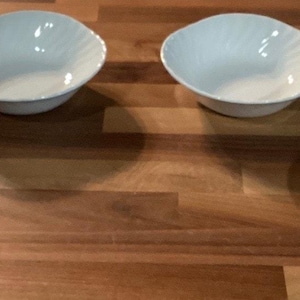 Puede incluir: Cuatro cuencos blancos de forma ovalada con un diseño texturizado y ondulado. Los cuencos están dispuestos sobre una superficie de madera, mostrando su diseño elegante y minimalista. Ideales para servir ensaladas, aperitivos o postres.