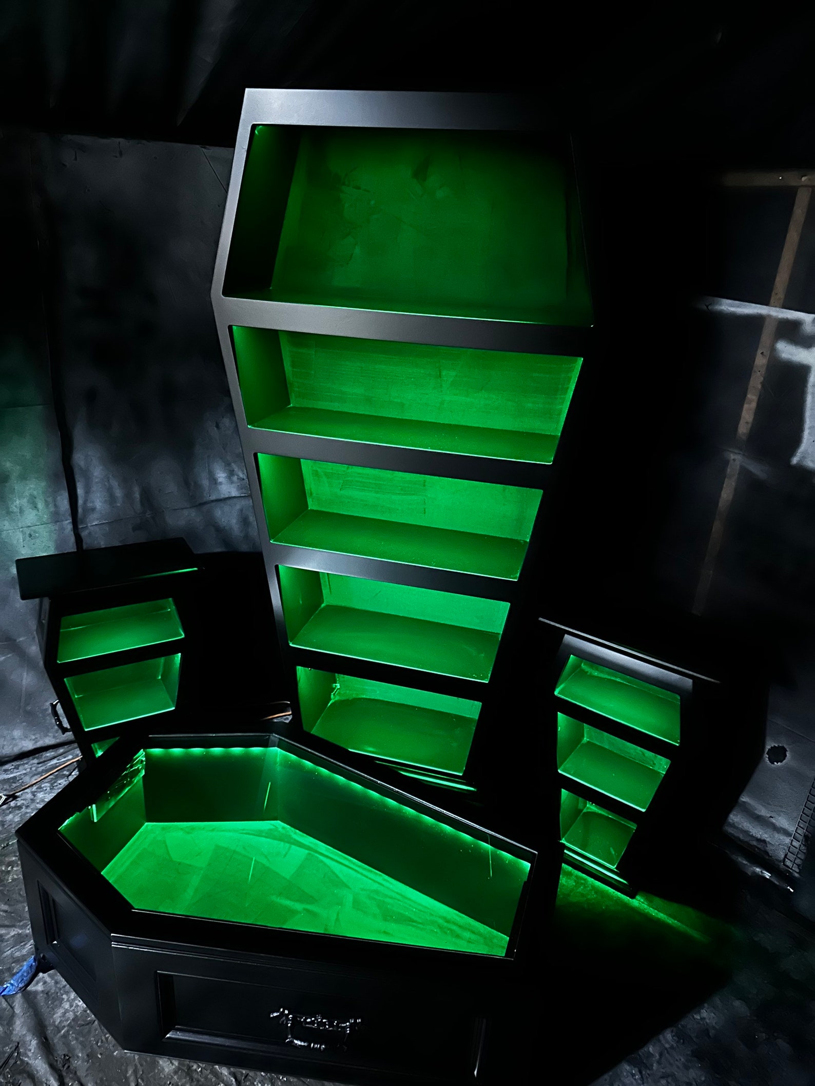 Gothic coffin furniture set illuminated with green LED lights, showing dramatic display of bookshelf, side tables, and coffee table