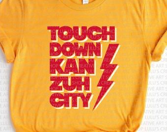 May include: Mustard yellow t-shirt featuring the text "TOUCH DOWN KAN ZUH CITY" in red and white, and a red and white lightning bolt graphic. The tee shirt is made of a soft material.