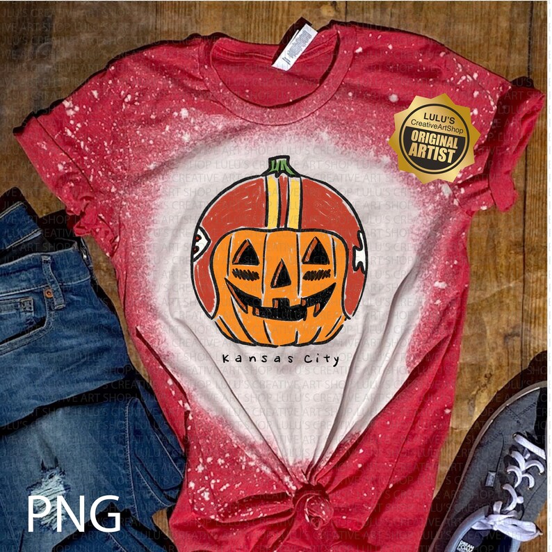 May include: Red and white tie-dye t-shirt featuring a pumpkin wearing a football helmet. The pumpkin has a carved face and is orange with a red and yellow helmet. The text "Kansas City" is below the pumpkin.