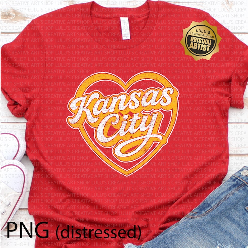 May include: Red t-shirt featuring a distressed design with the words "Kansas City" in a heart-shaped graphic. The design has a vintage look with yellow and white lettering. Includes a gold seal that says "Original Artist".
